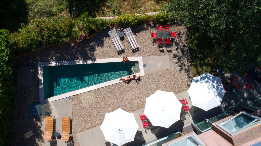 Espace détente avec chaises longues et parasols au bord de la piscine vue de haut, hotel montagne corse, Boutique Hôtel Artemisia.